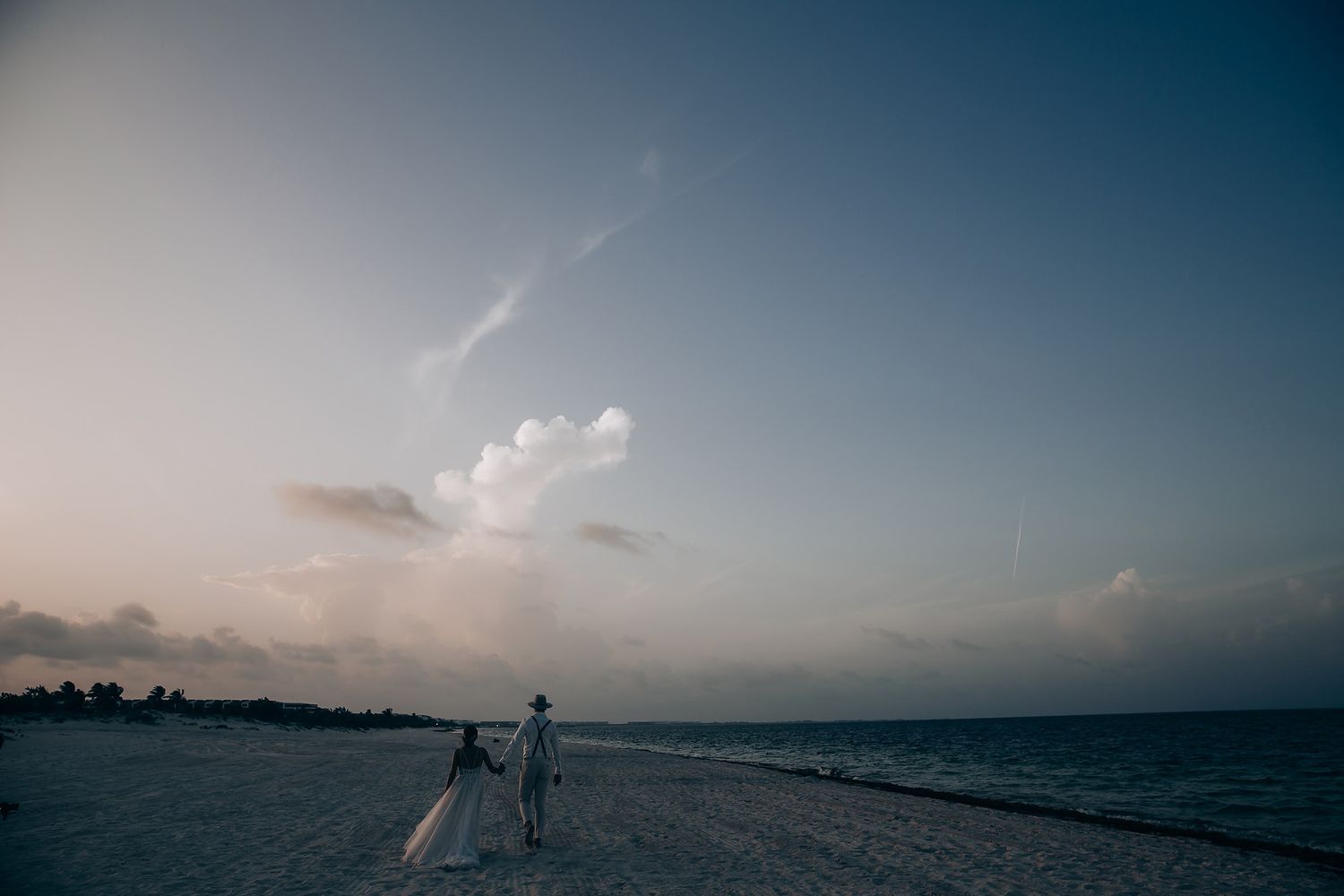 Panoramic sunset view of a tropical beach with cloudy horizon.