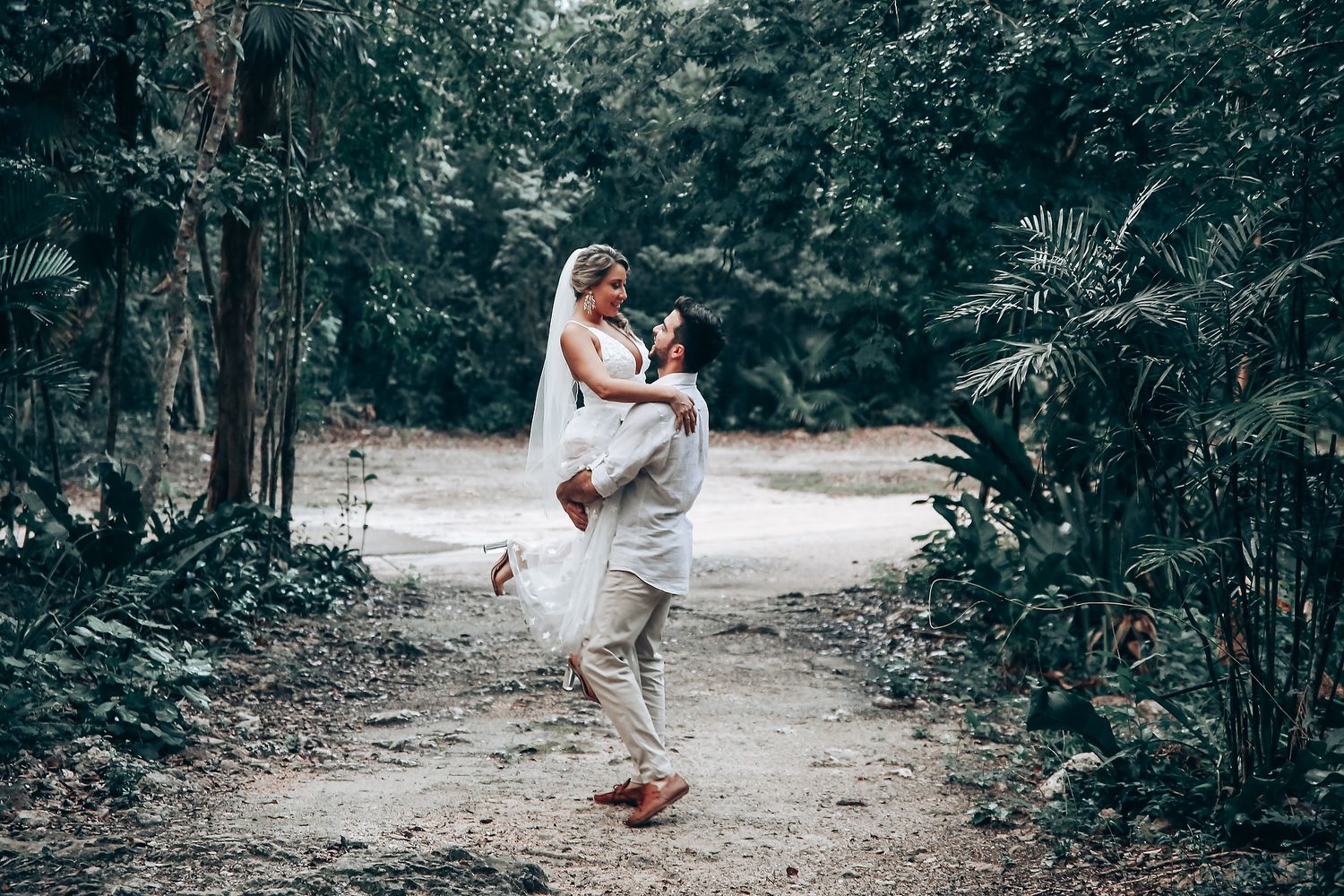 A joyful moment captured on a forest path during a wedding celebration.