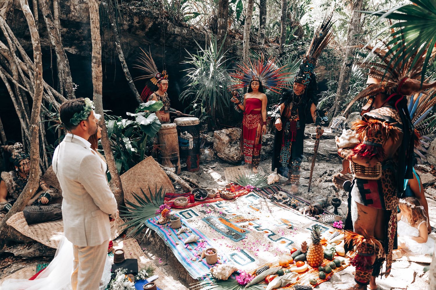 Traditional ceremony in a lush tropical forest setting with ceremonial decorations and attendees.
