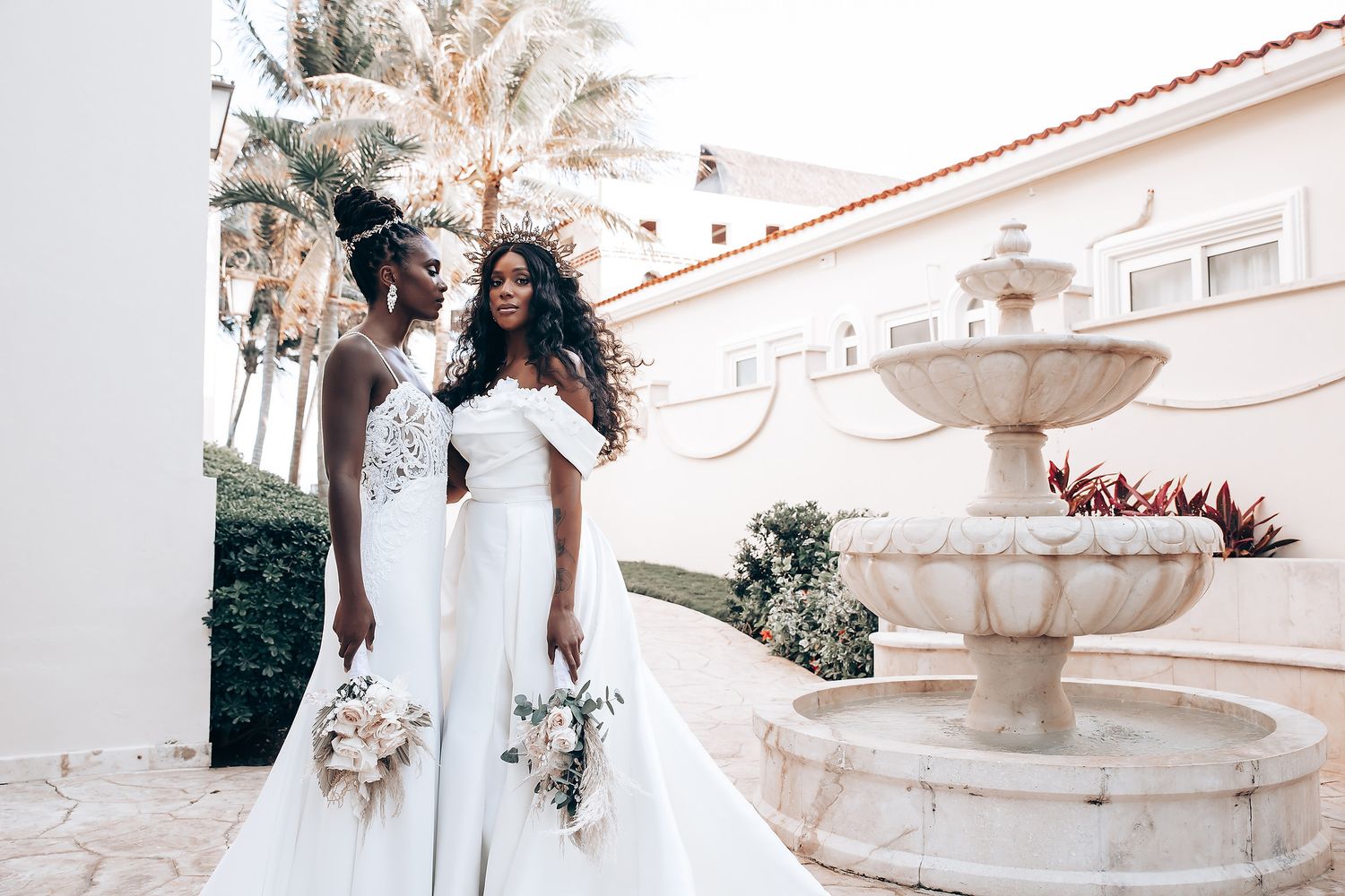 Elegant bridal party in white dresses photographed against a Spanish colonial style building.