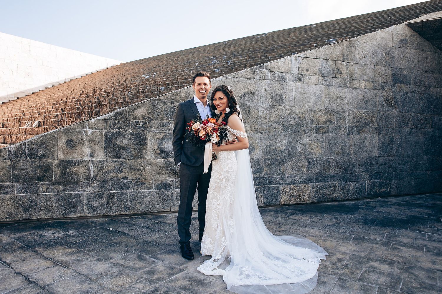 Romantic wedding couple poses against stone walls at sunset in series of candid moments.