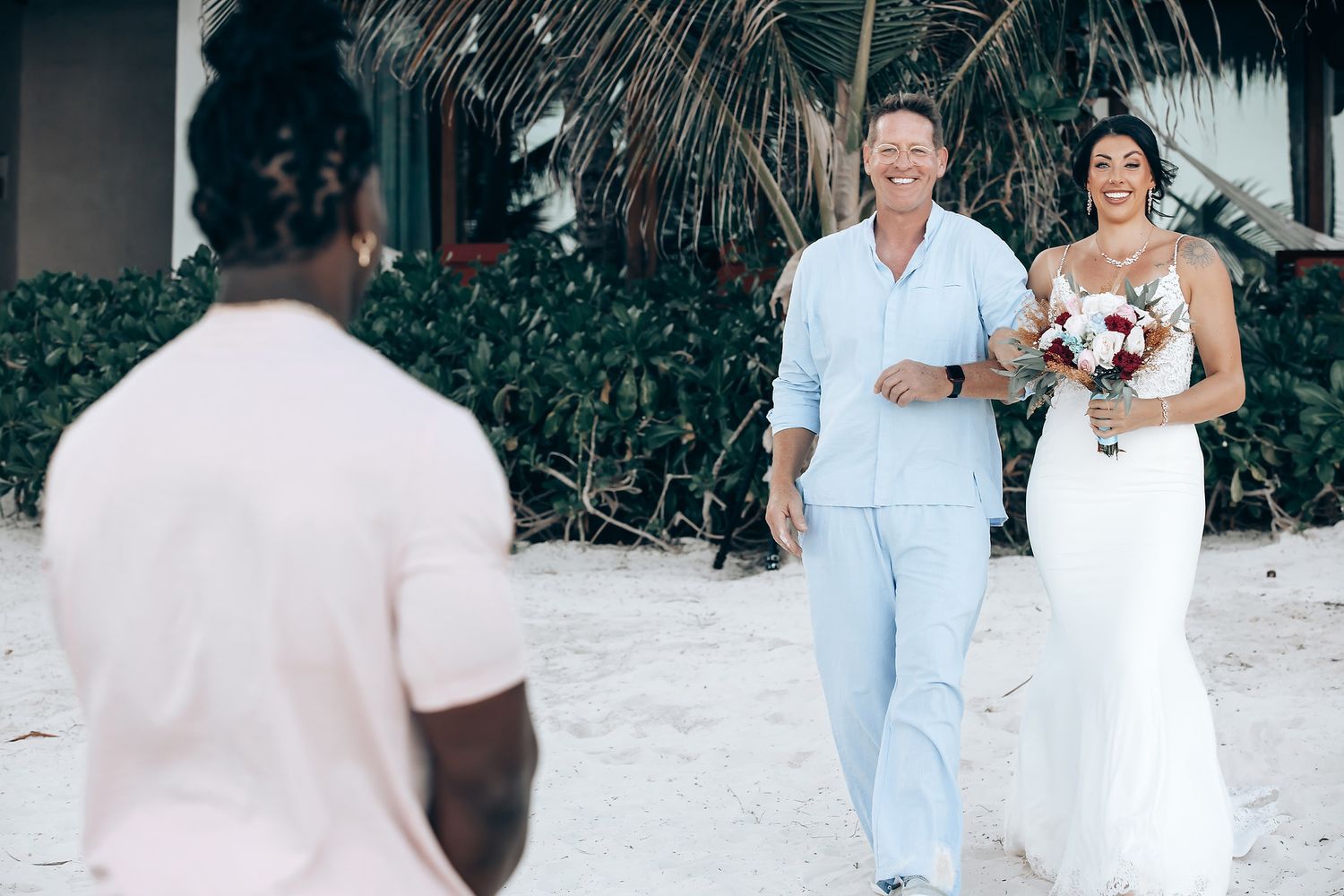 A wedding ceremony on a beach with a couple and their guests walking together.