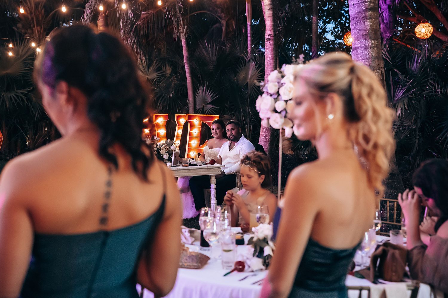 Wedding reception guests gather at an outdoor evening celebration with illuminated decor.