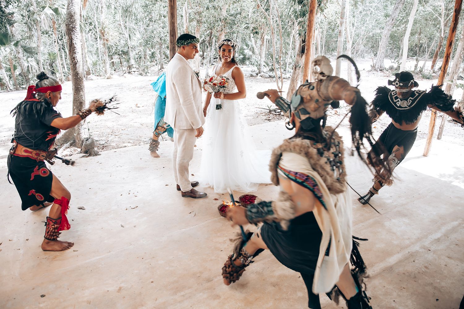 Traditional dancers in ceremonial costumes perform during a wedding celebration in a covered outdoor space.