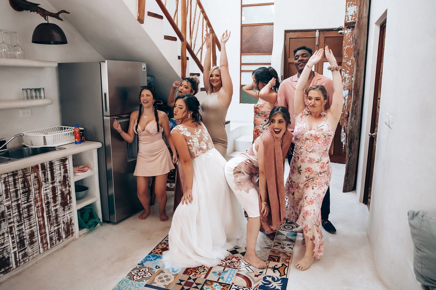 Bridesmaids in pink dresses help the bride get ready in a bright indoor space.
