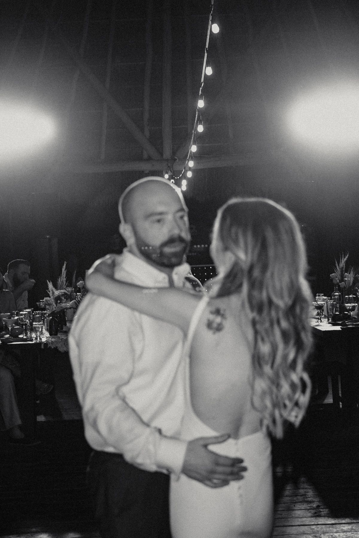 Black and white photo of a couple sharing an intimate first dance at their wedding reception.