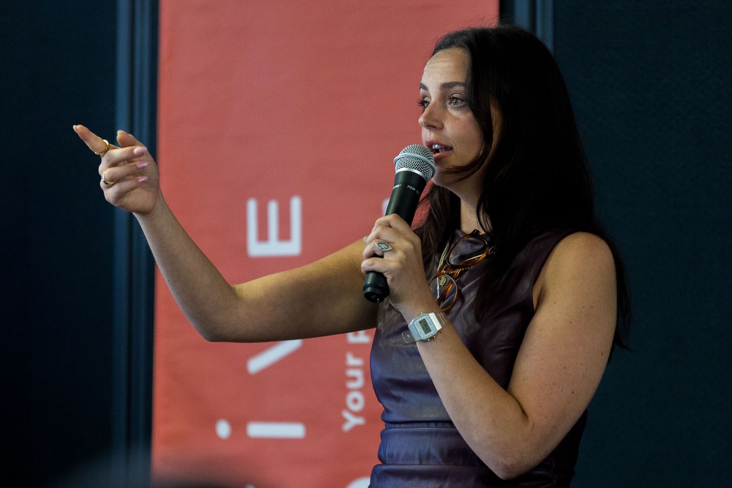 Speaker presenting on stage against a red background at a conference.