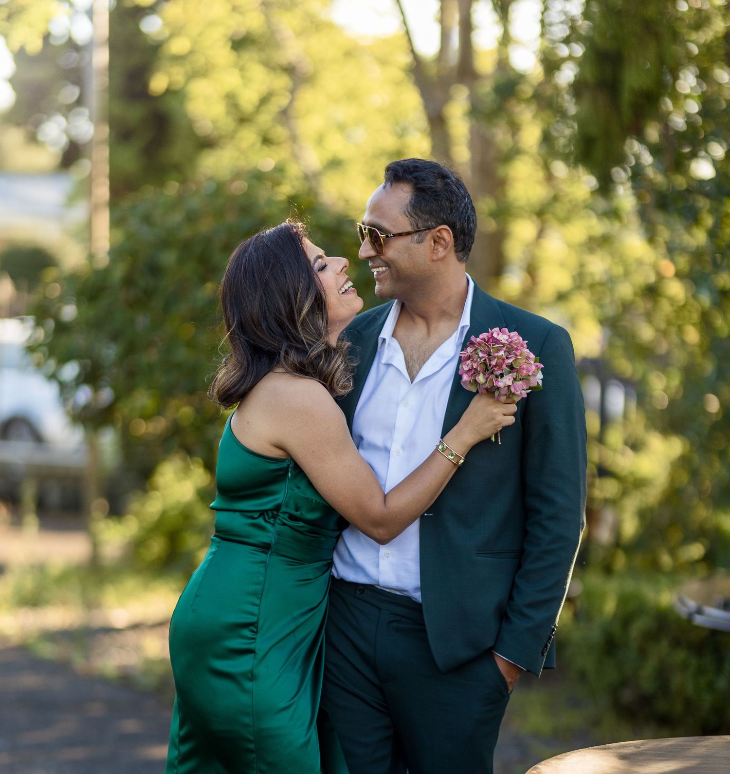 Romantic couple embracing outdoors with bride holding a pink bouquet.