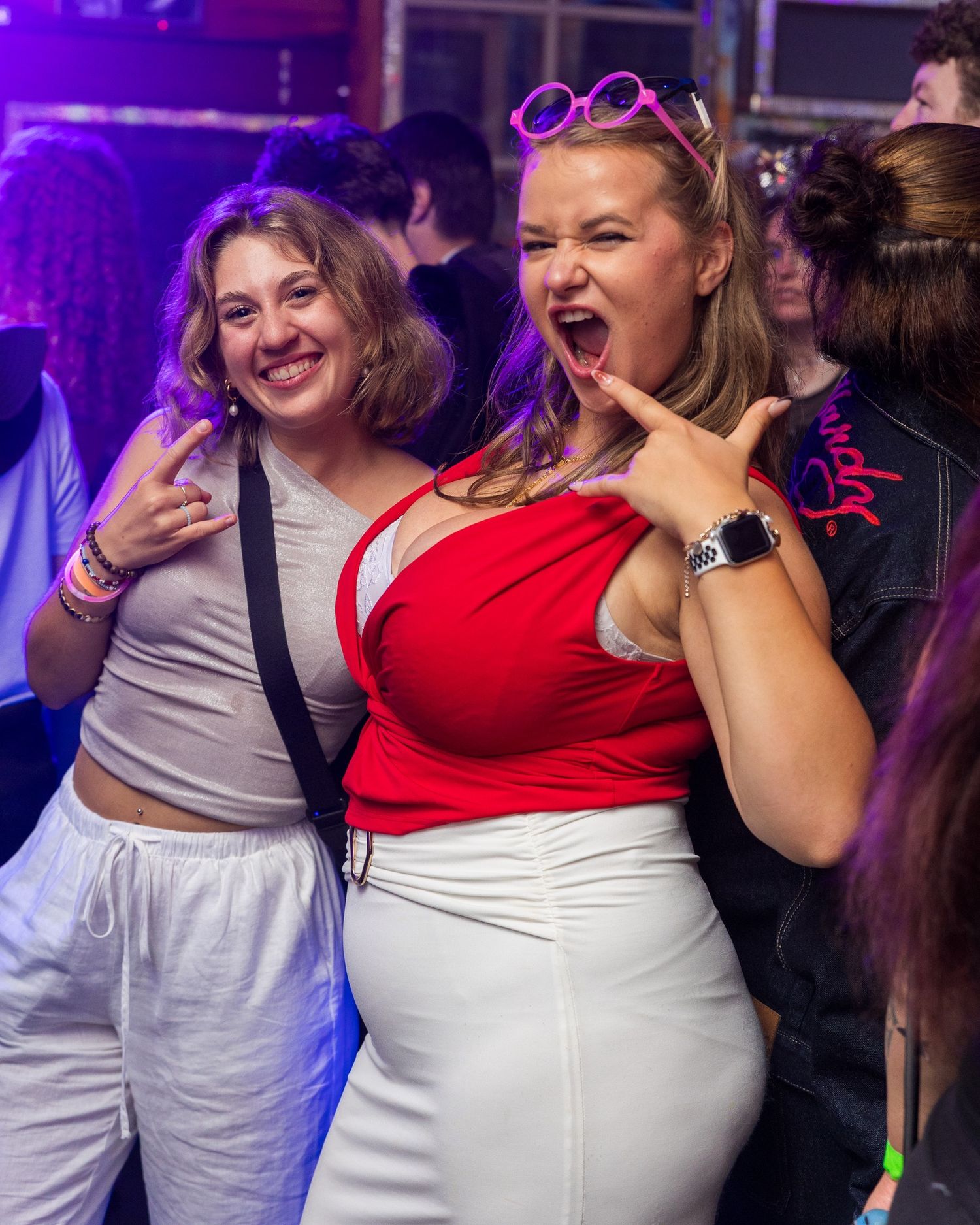 Friends in casual attire enjoying themselves at a party with purple lighting.