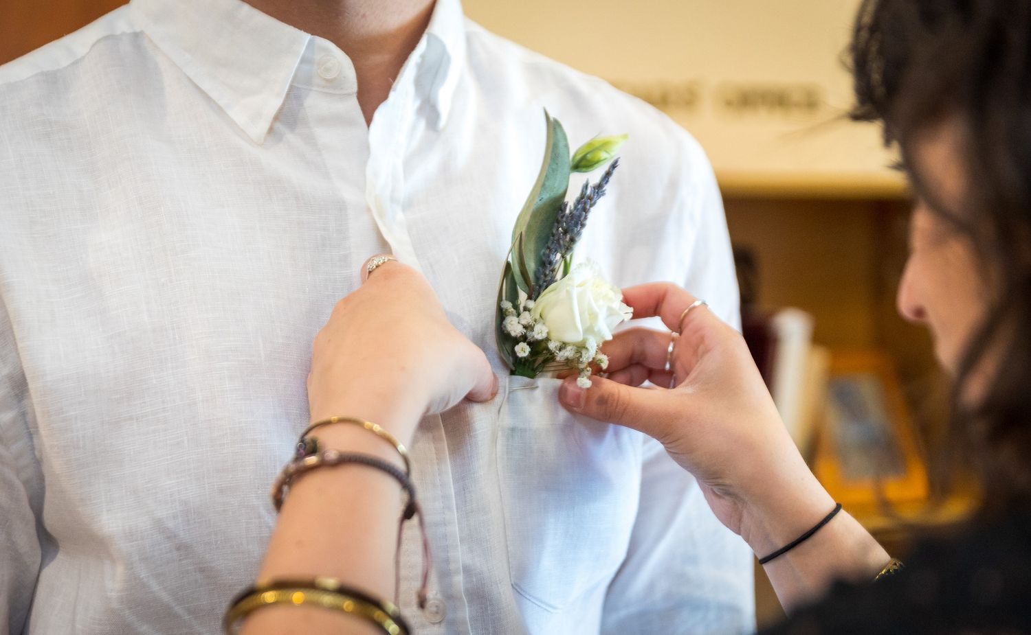 Wedding ceremony detail showing hands exchanging rings against a warm-toned background.
