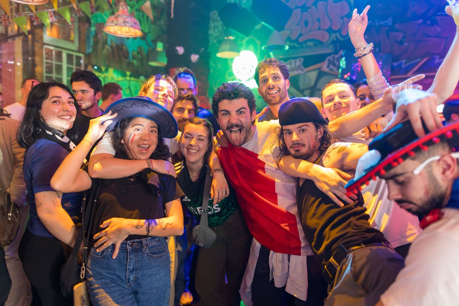 Crowd celebrating at a nightclub with vibrant blue and purple lighting effects.