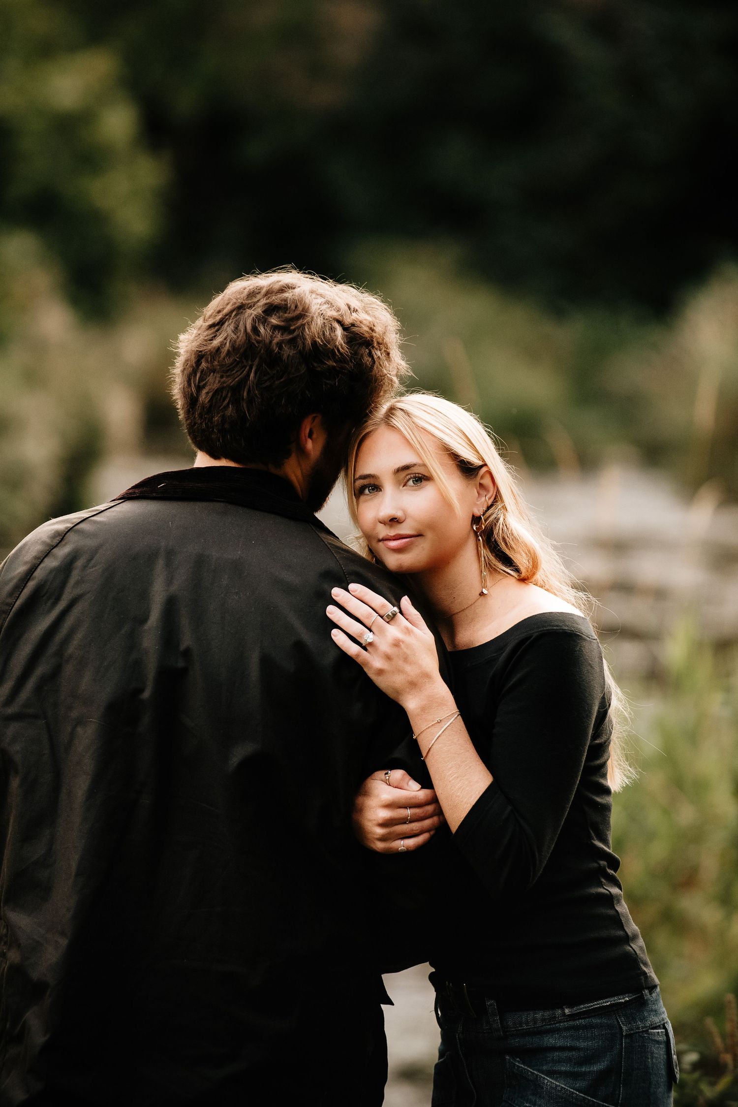 A romantic couple embraces in a series of intimate black and white photos against a natural outdoor backdrop.