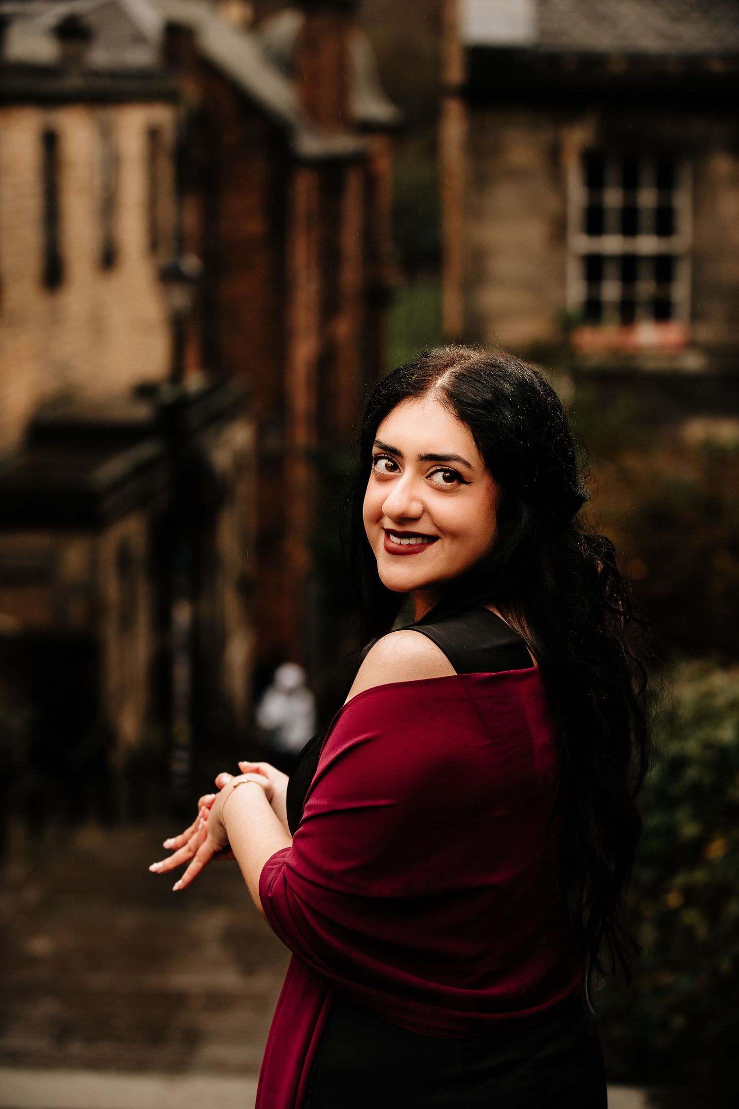 Portrait in burgundy dress against historic Edinburgh architecture.