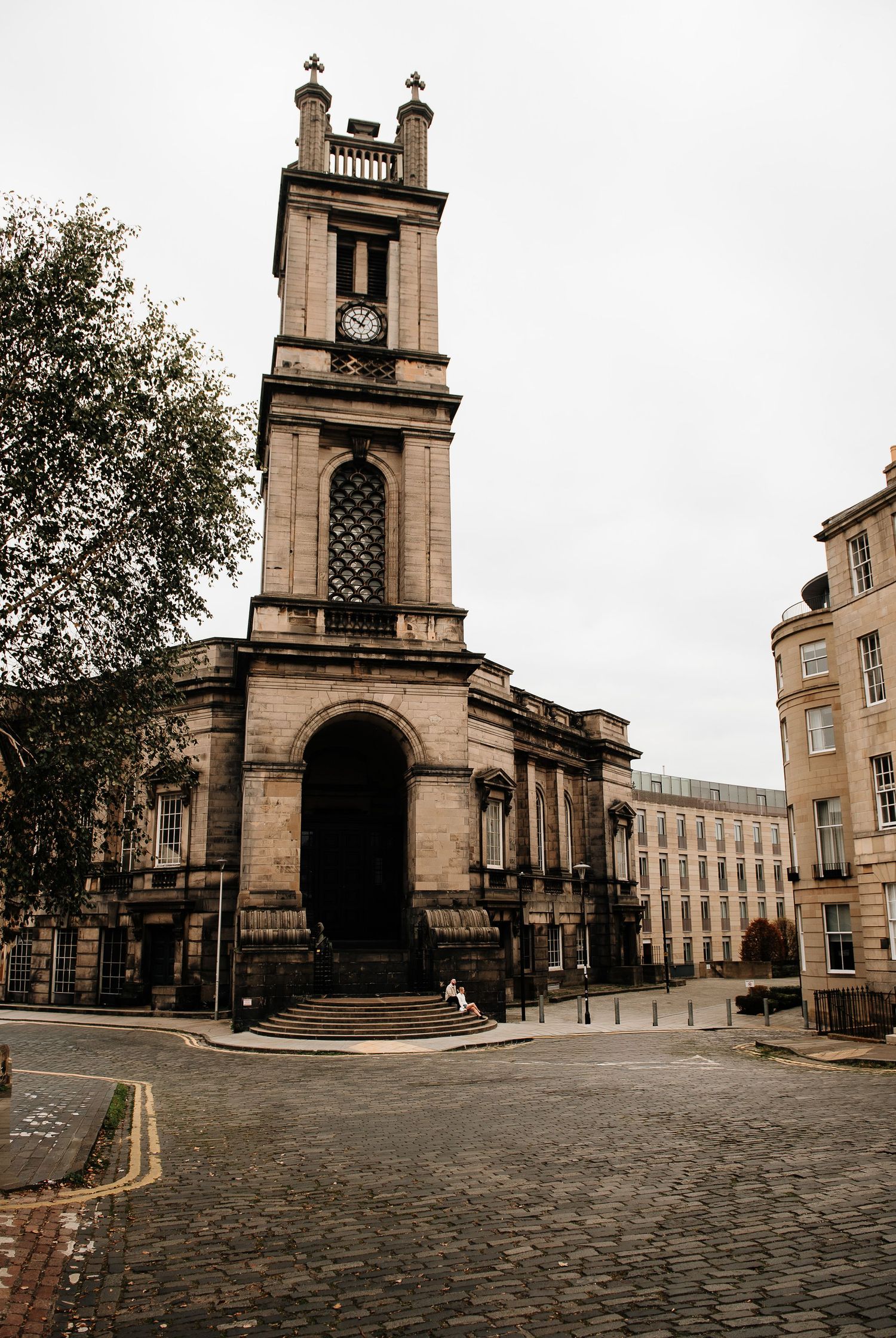 Historic church architecture and cobblestone plaza in Edinburgh with stone buildings.