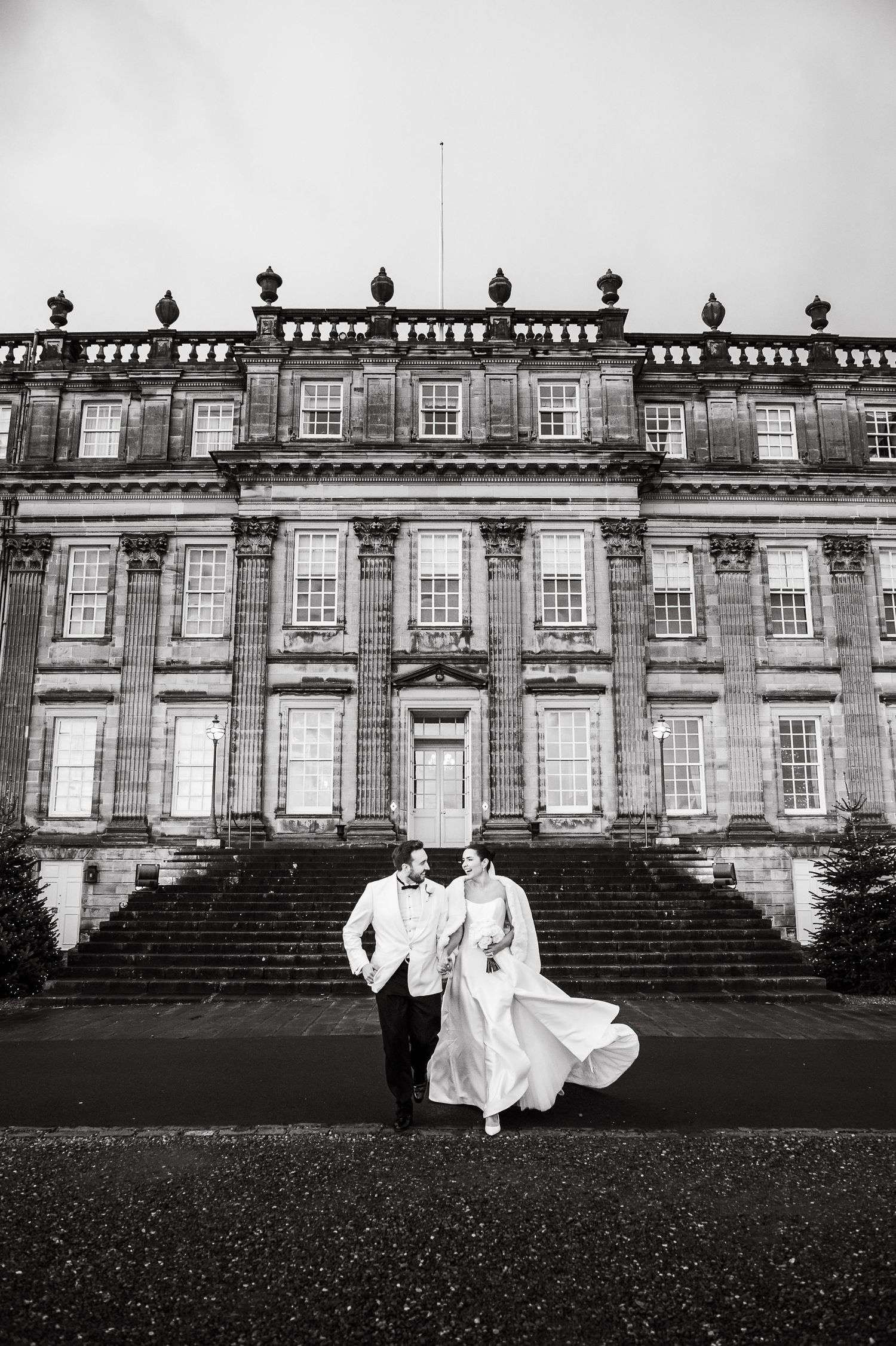 A grand historic mansion with ornate architectural details serves as backdrop for a romantic black and white wedding photo series.