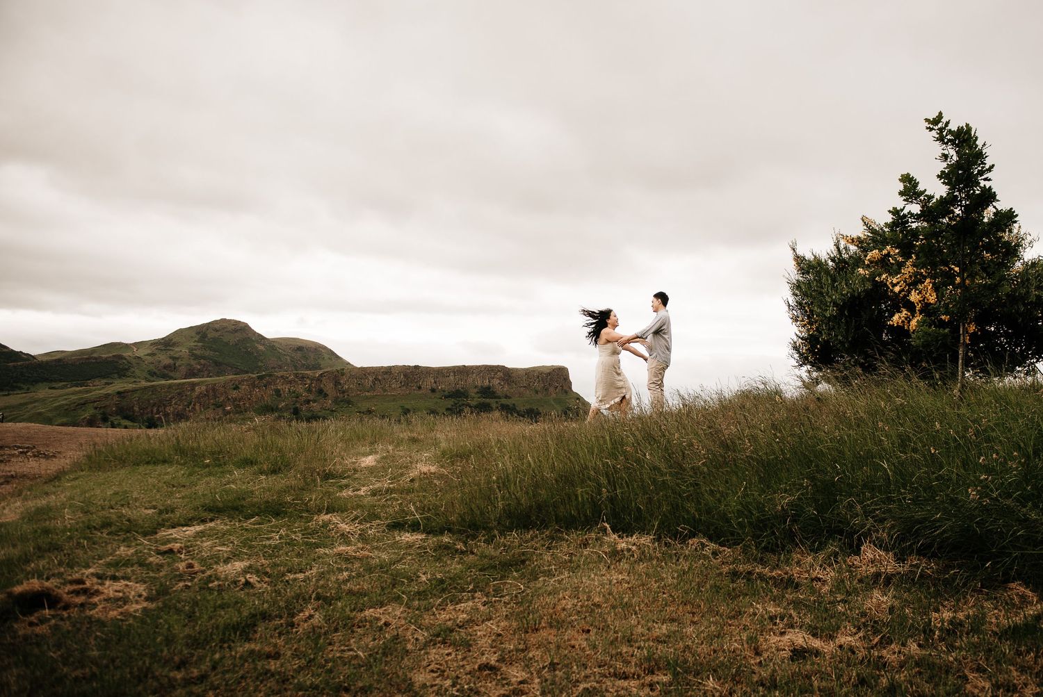 Scenic hilltop landscape with figures silhouetted against a cloudy sky.