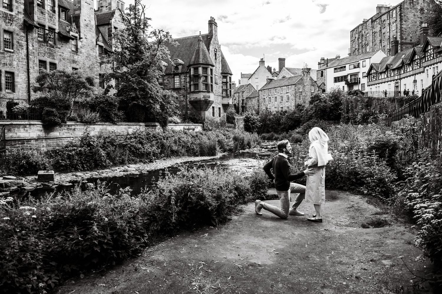 Black and white photo of a man proposing to a woman on a garden path in Edinburgh, Scotland.