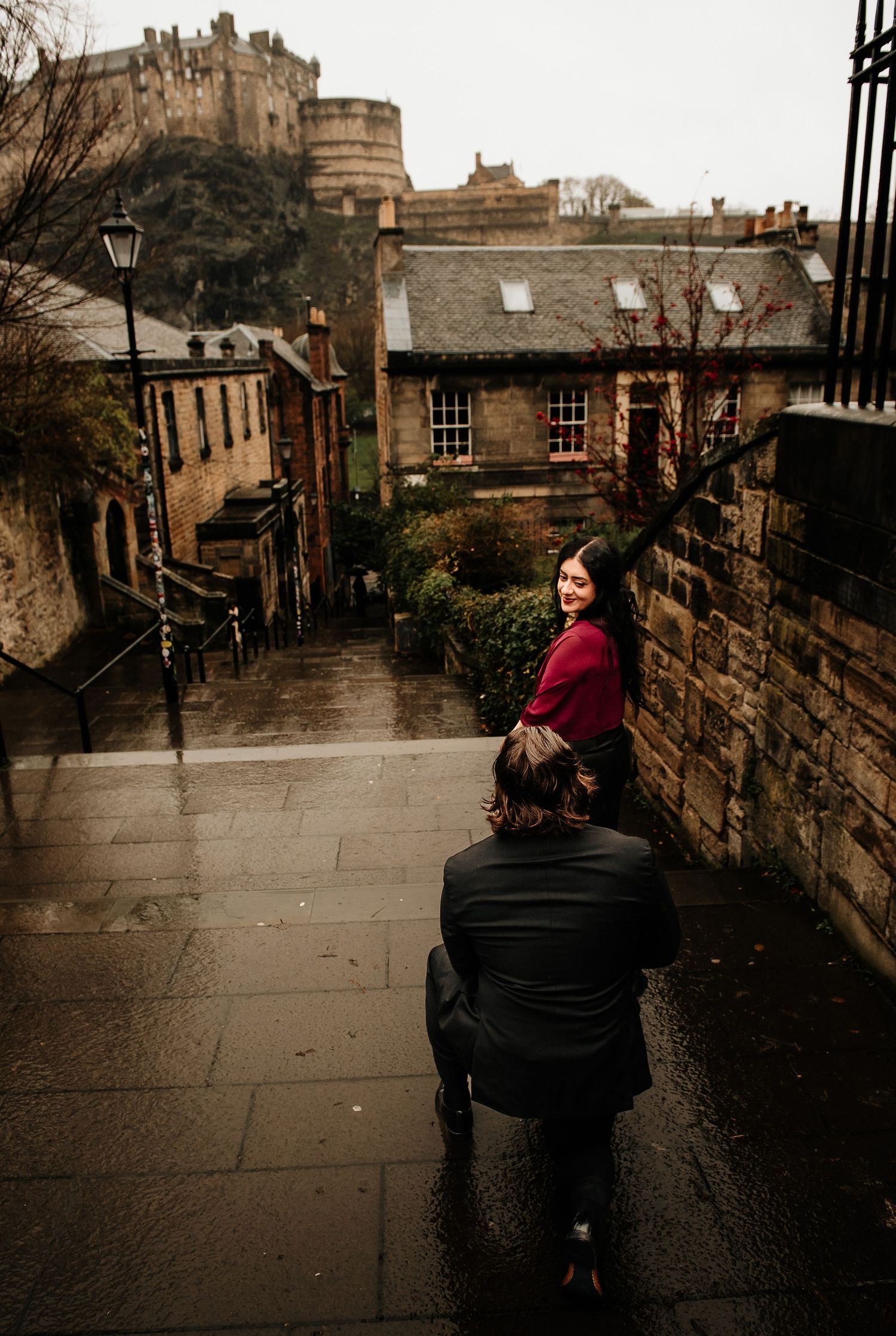 A photographer captures a moment on historic steps leading to Edinburgh Castle on a moody day.