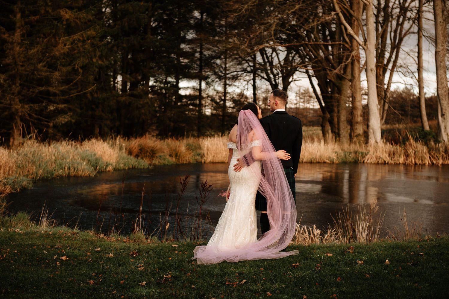 Romantic wedding portraits captured in golden evening light among trees.