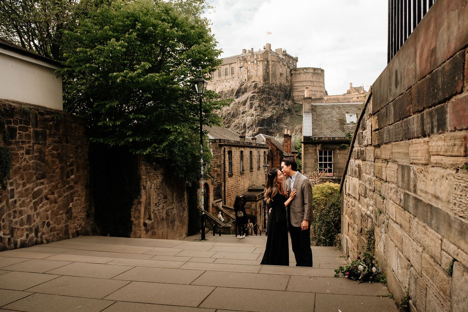 Historic stone buildings and narrow alleyways line a cobblestone street in Edinburgh's old town.