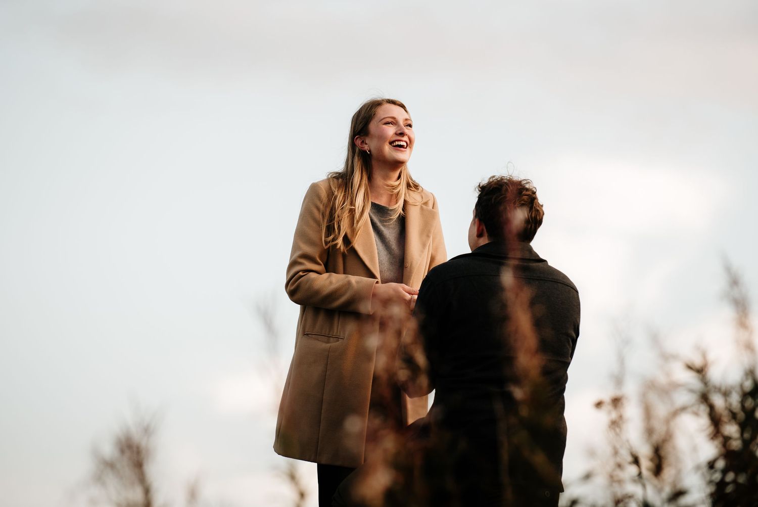 Silhouettes against bright sky during golden hour on a hilltop.