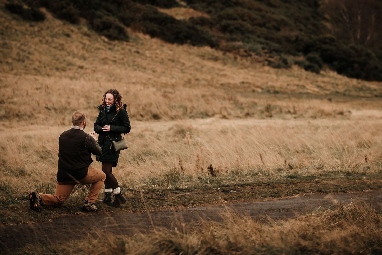 Couple walking along a grassy hillside path on an autumn afternoon.