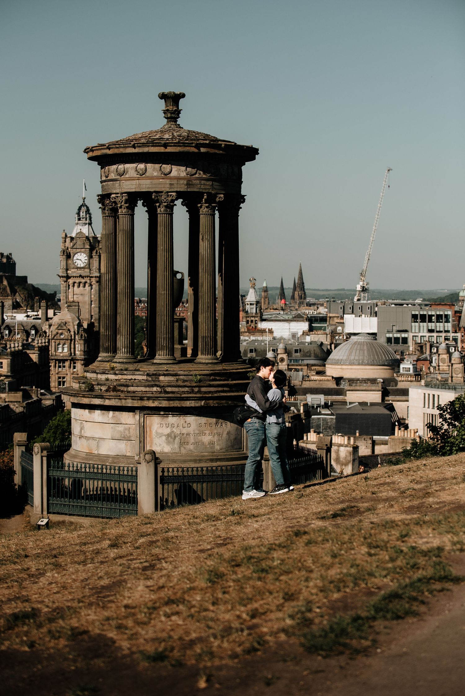 Calton Hill monuments overlooking Edinburgh's historic cityscape on a clear day.