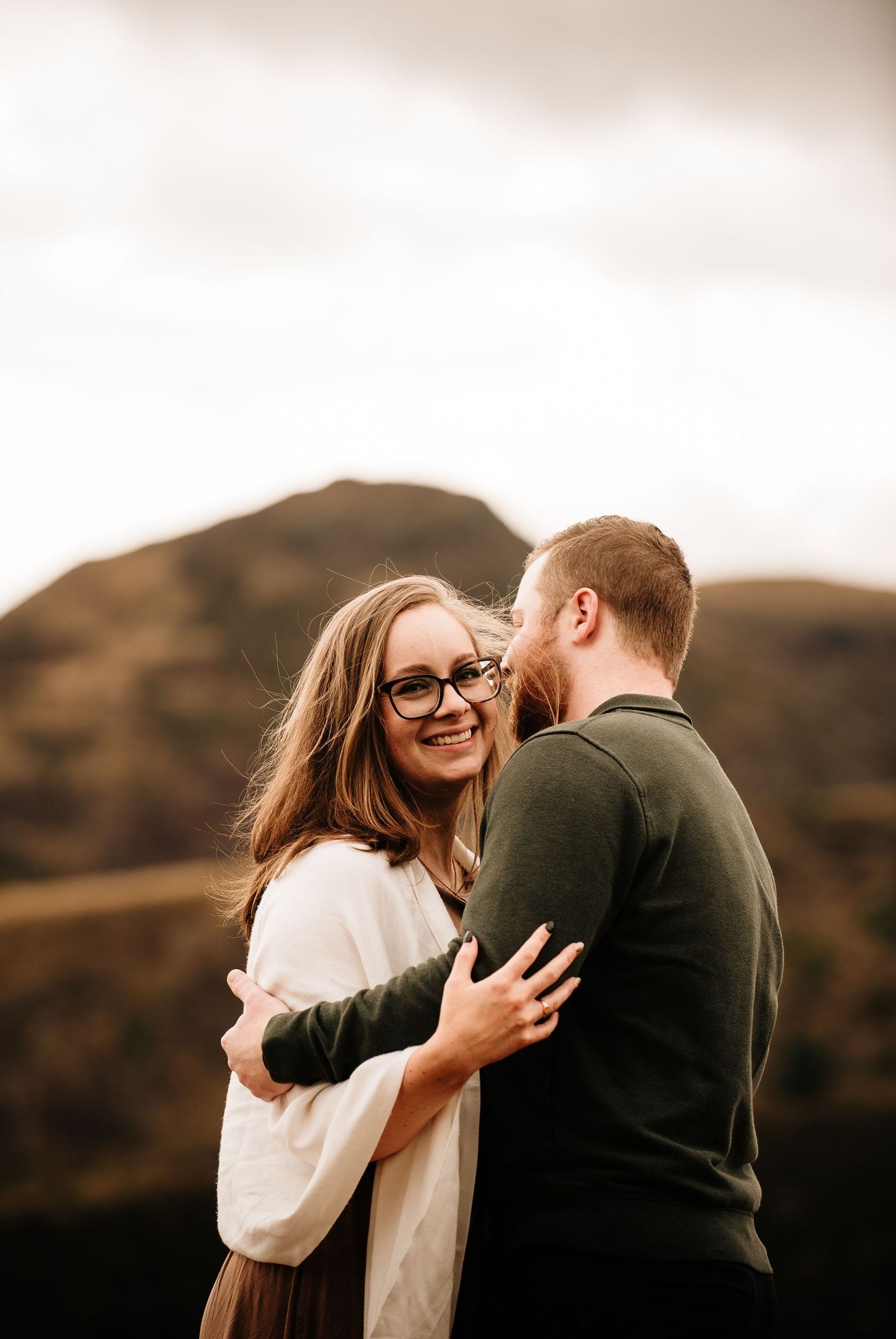 Intimate embrace captured during an autumn engagement session on a hillside.