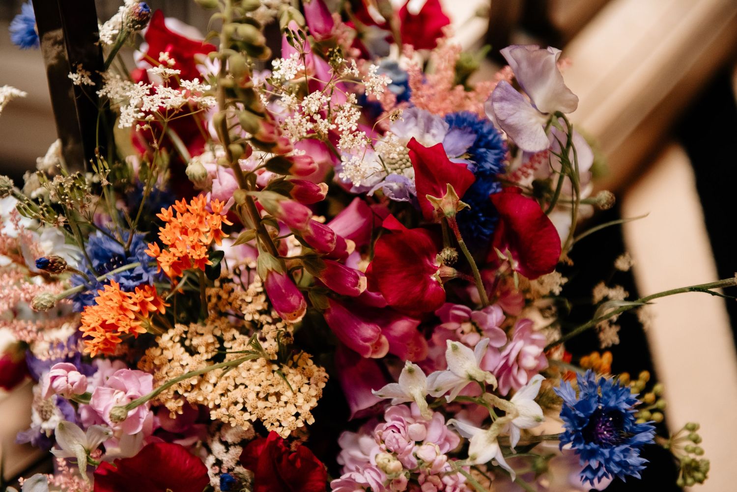 Vibrant floral arrangements featuring pink, red, and blue blooms create a romantic wedding backdrop.