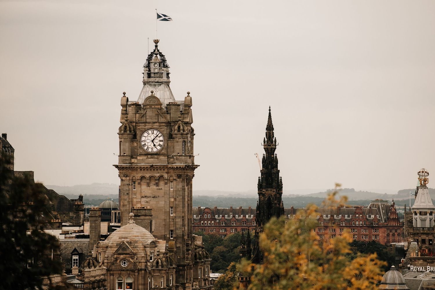 Historic Edinburgh skyline featuring iconic architecture and clock tower under moody skies.