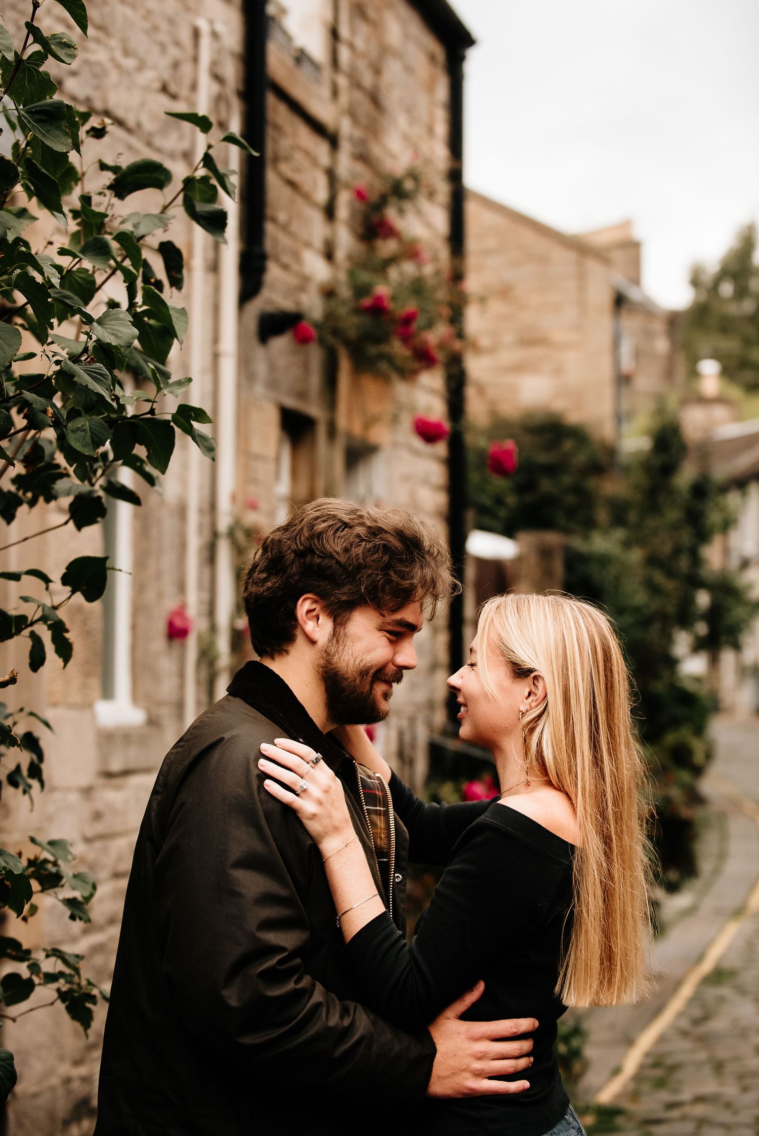 A tender moment shared on a charming cobblestone street lined with historic buildings.