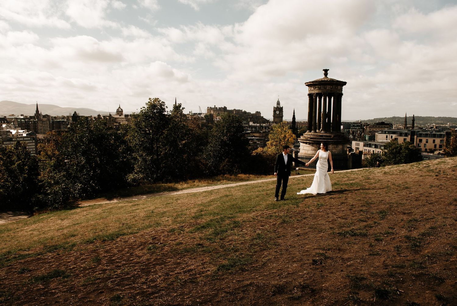 Panoramic view of Edinburgh's historic skyline with Calton Hill monuments at sunset.