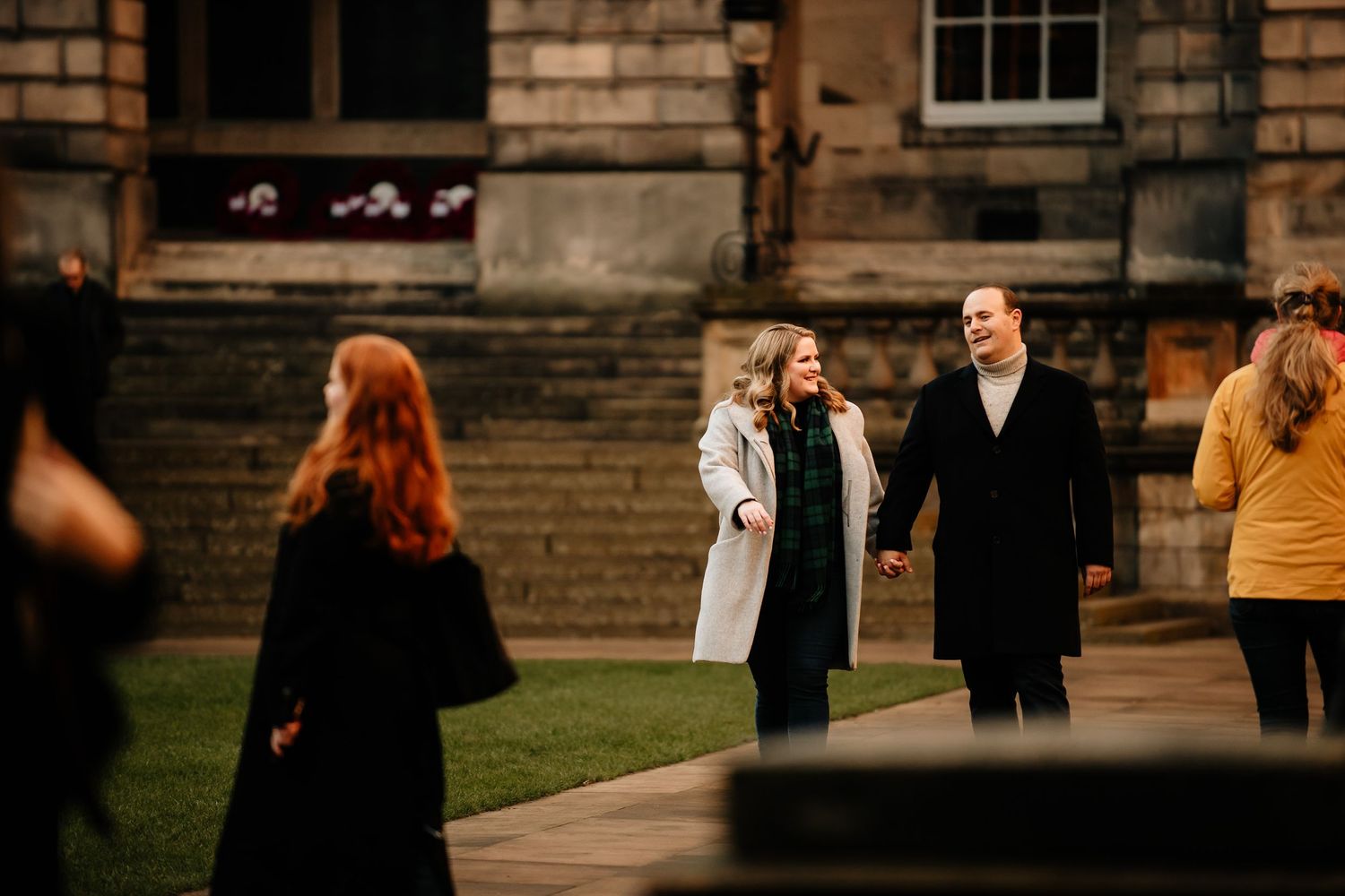 A wedding party walks along a brick building exterior during golden hour lighting.