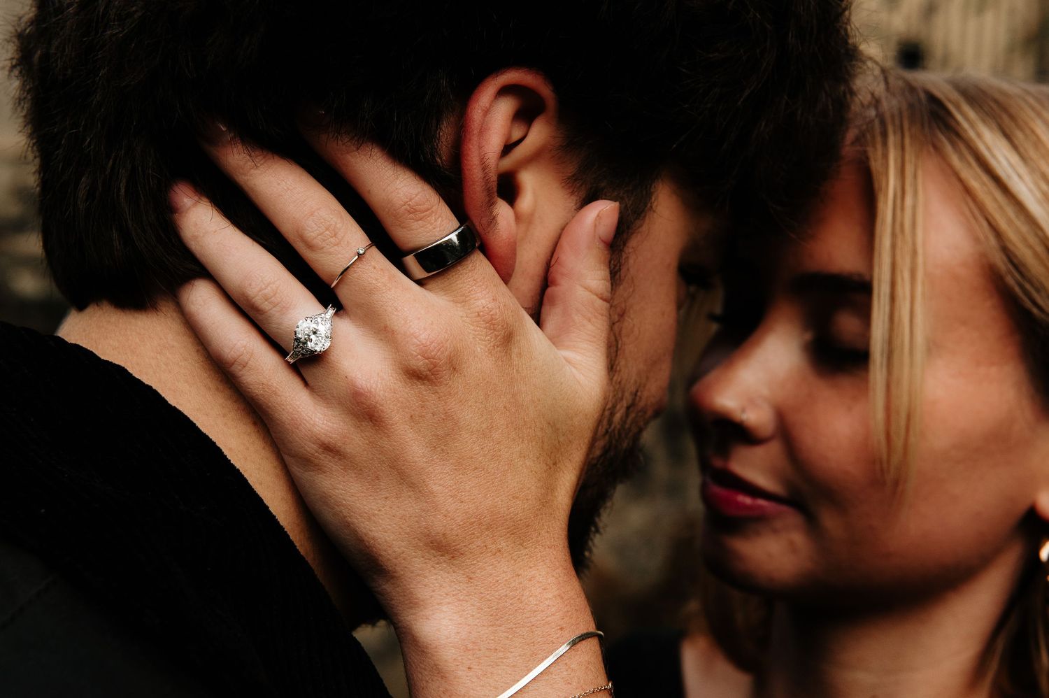 Close-up romantic moment captured against blurred historic architecture.