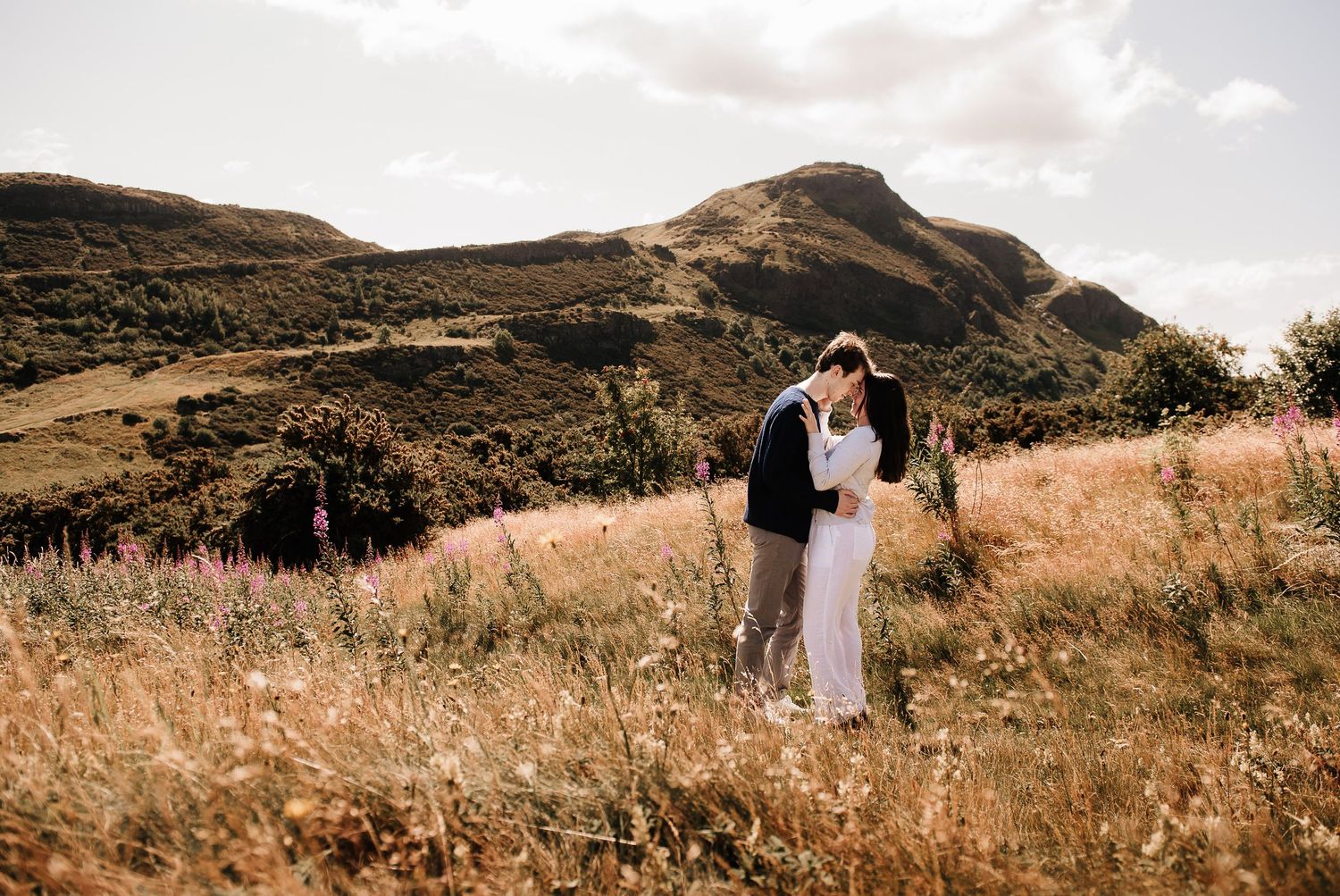 Rolling hills and mountains create a dramatic landscape backdrop for an intimate moment.