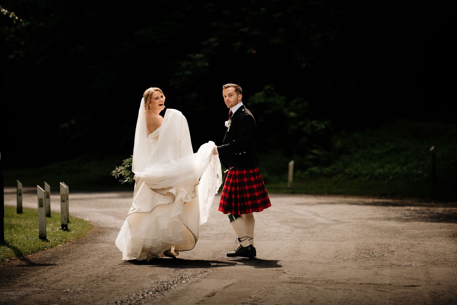 Wedding couple walking along a shadowy garden path.