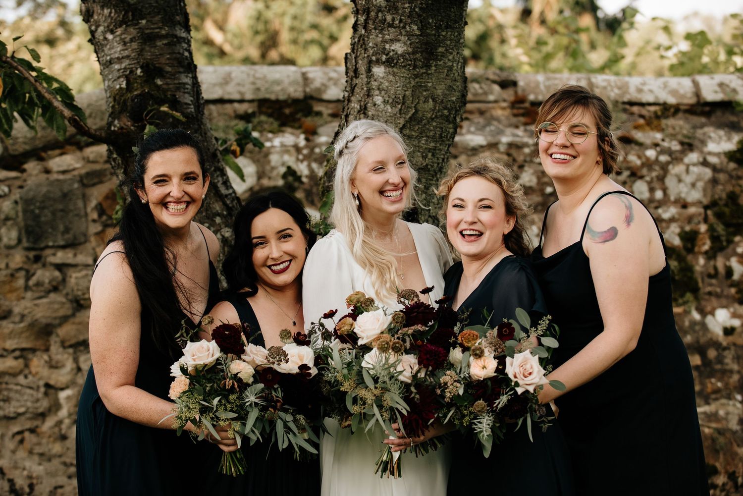 Wedding party celebrates together in outdoor garden setting.