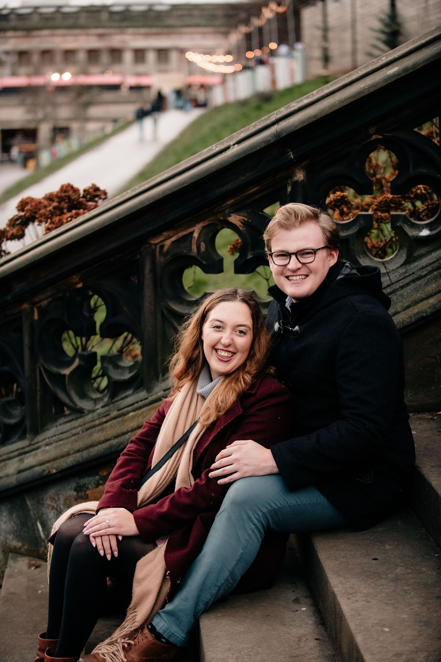 A couple shares joyful moments together while sitting on stone steps during an outdoor photoshoot.