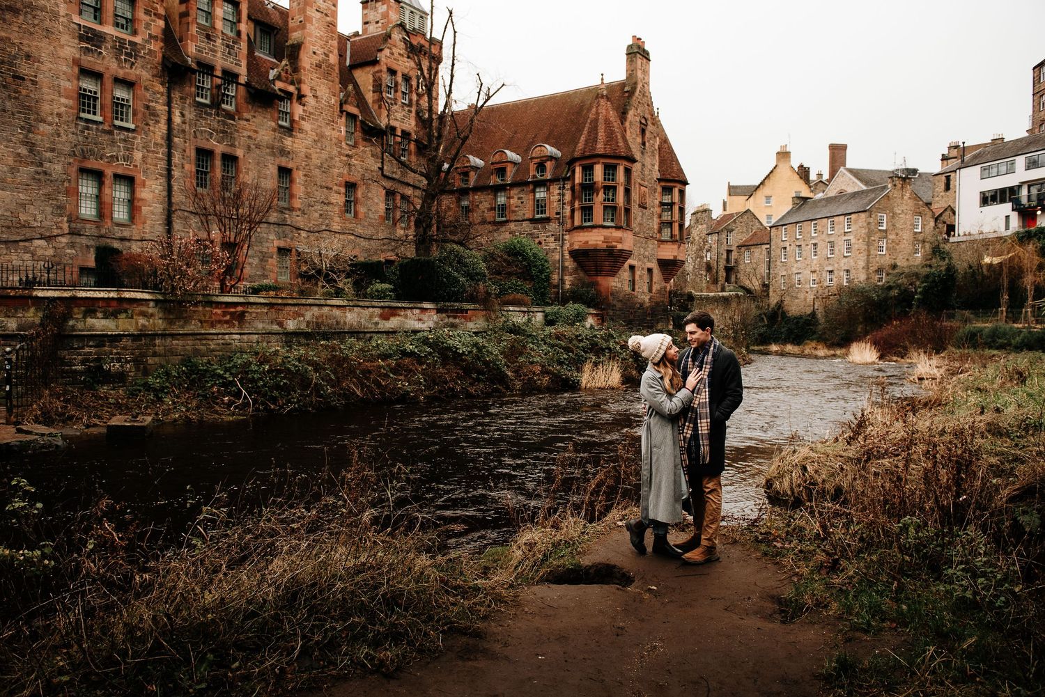 Couple walking along historic stone buildings and pathways in Edinburgh.