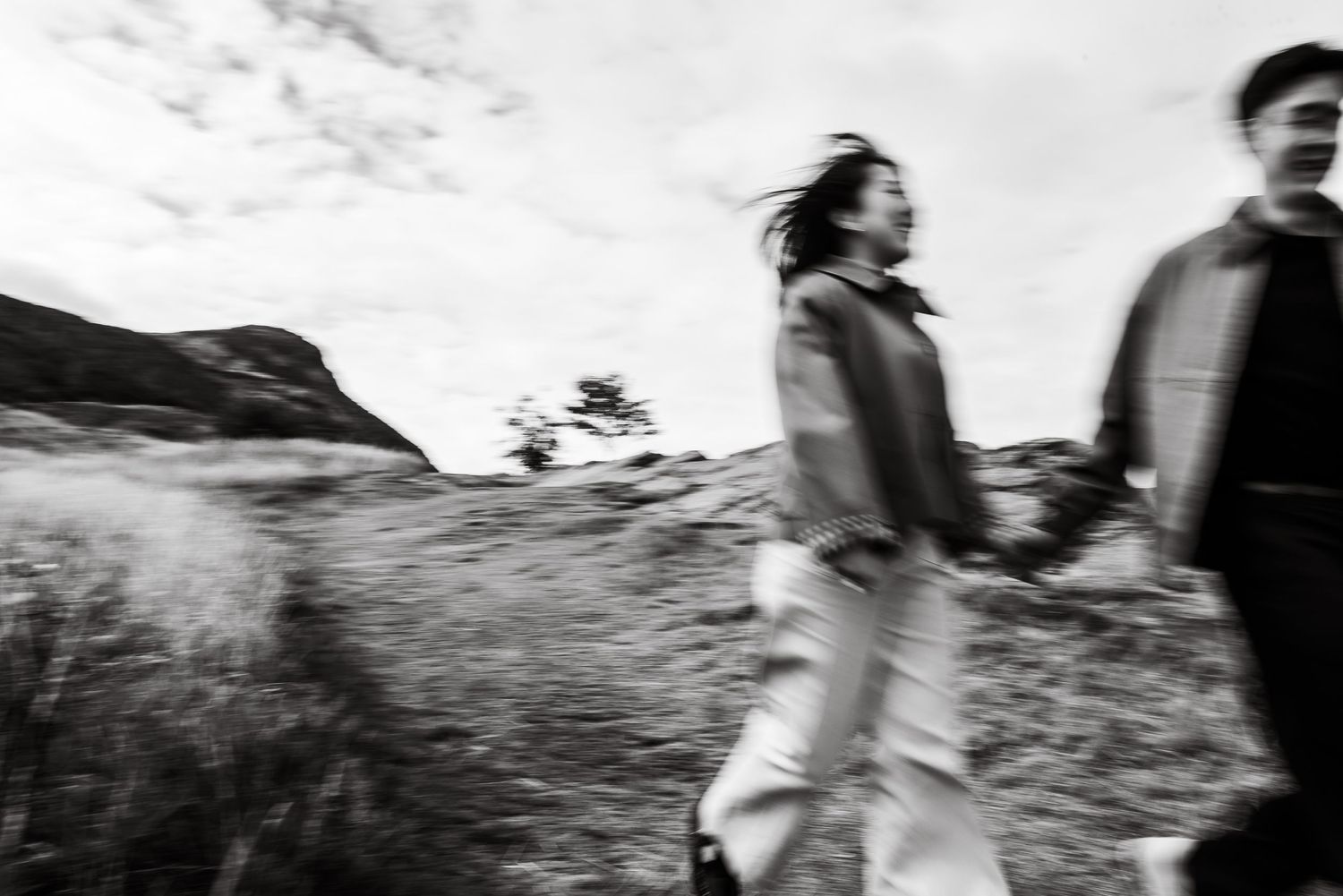 Motion blur captures people walking through windswept mountain grassland.