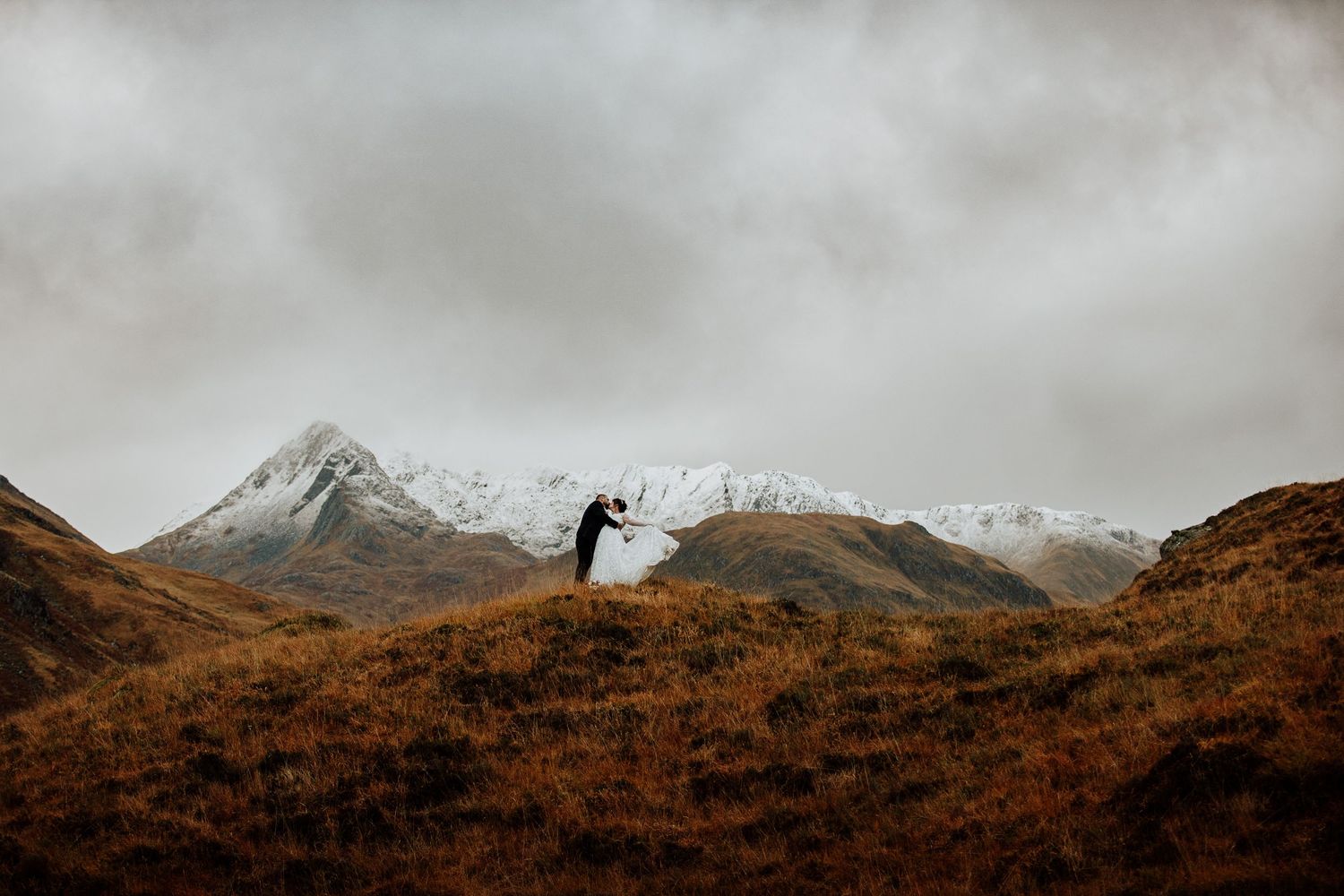 Sweeping Scottish Highland vista with snow-capped mountains in background.