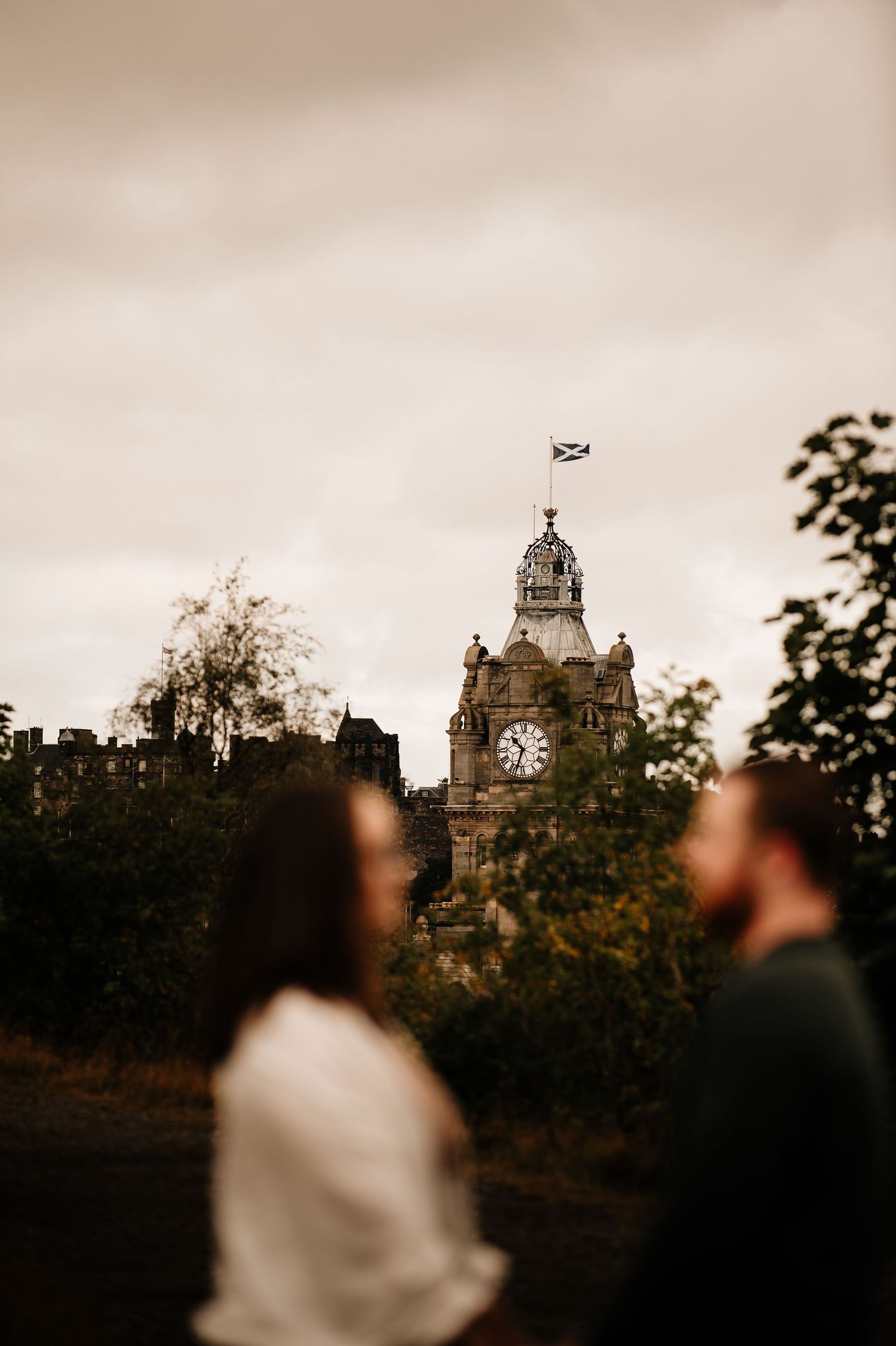 Silhouetted couple against Edinburgh's historic skyline during golden hour.