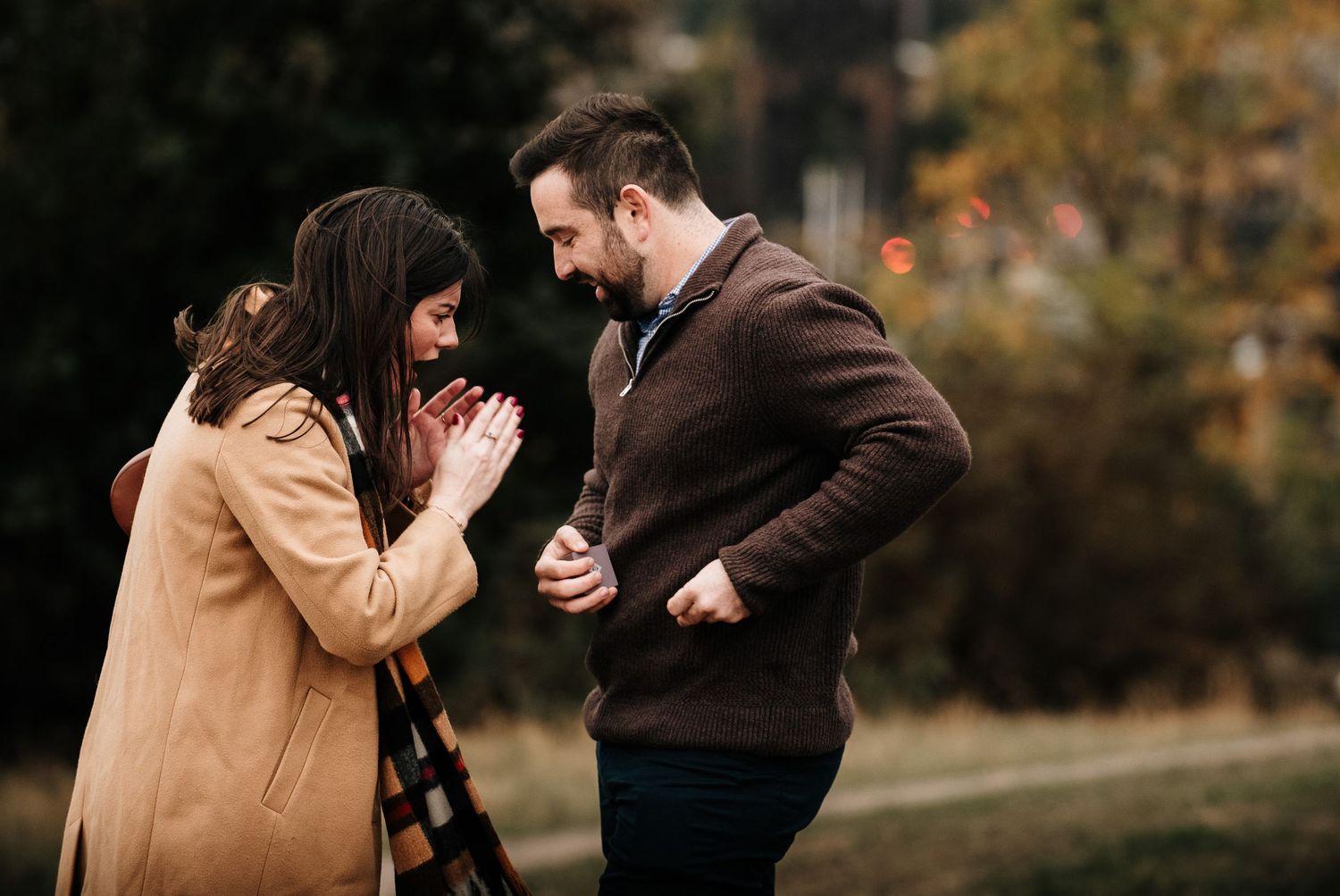 A romantic autumn proposal moment captured at Calton Hill in Edinburgh with historic monuments in the background.