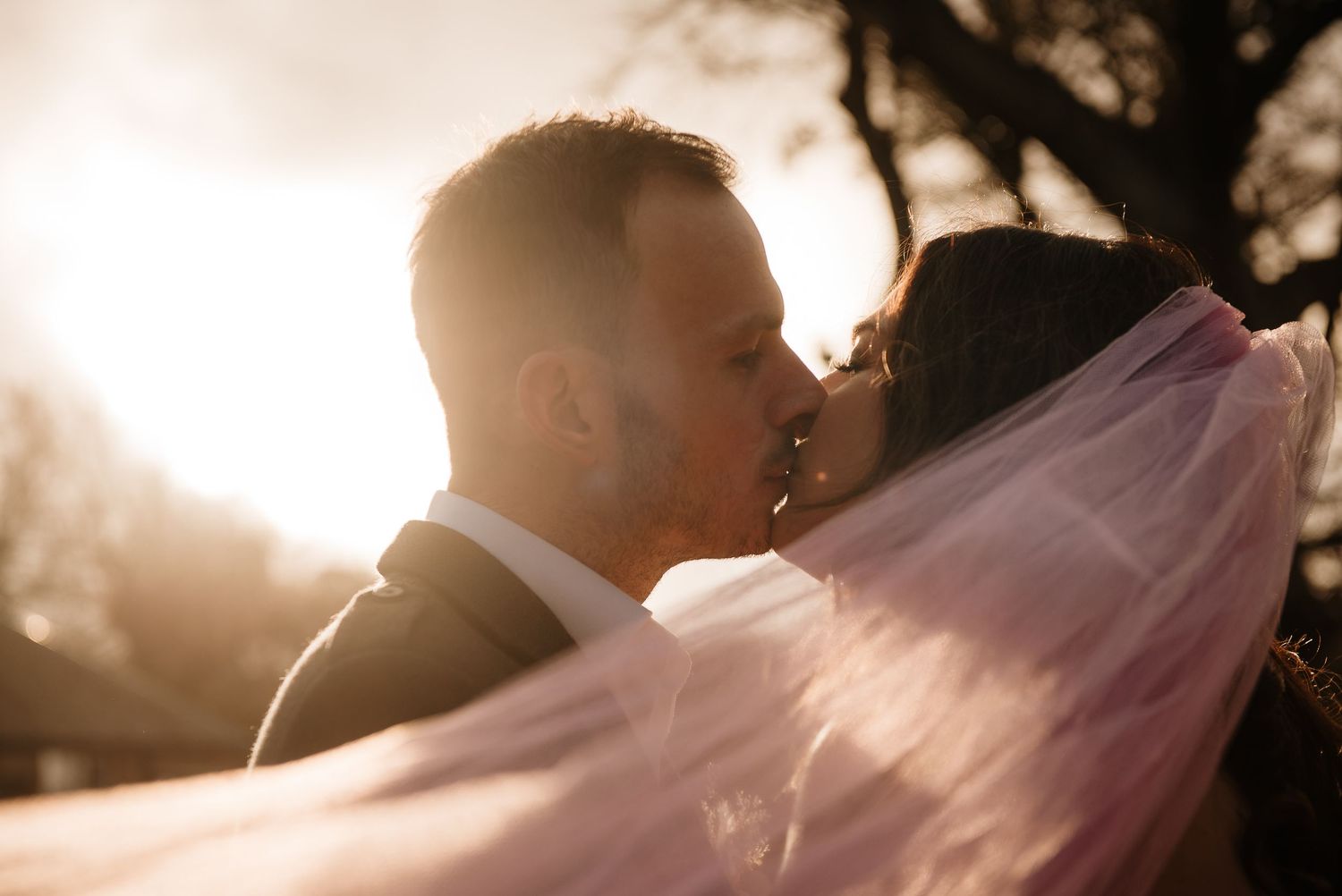 Backlit wedding couple silhouetted against golden sunset light.
