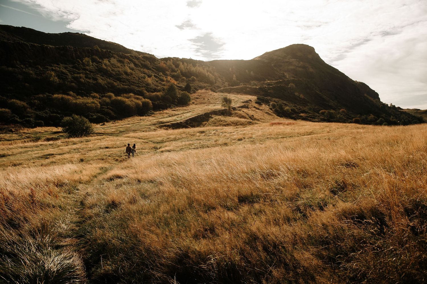 Panoramic view of rolling hills and mountains under a moody cloudy sky.