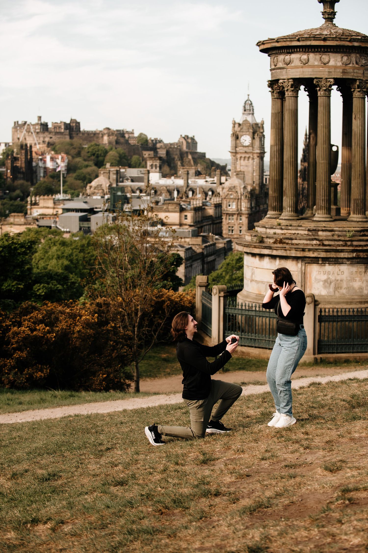 Surprise proposal moment at Calton Hill with Edinburgh's historic backdrop.