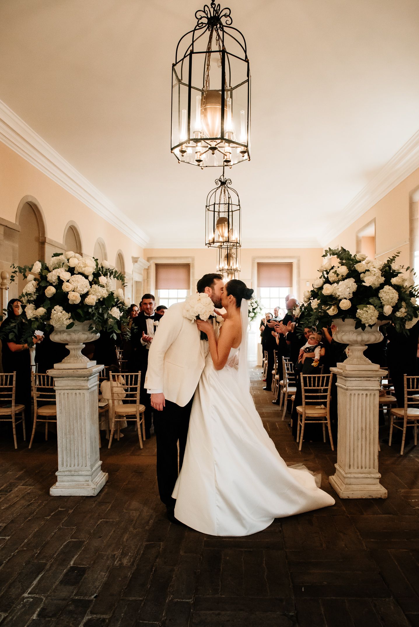 Romantic ballroom reception with ornate pillars and floral arrangements.