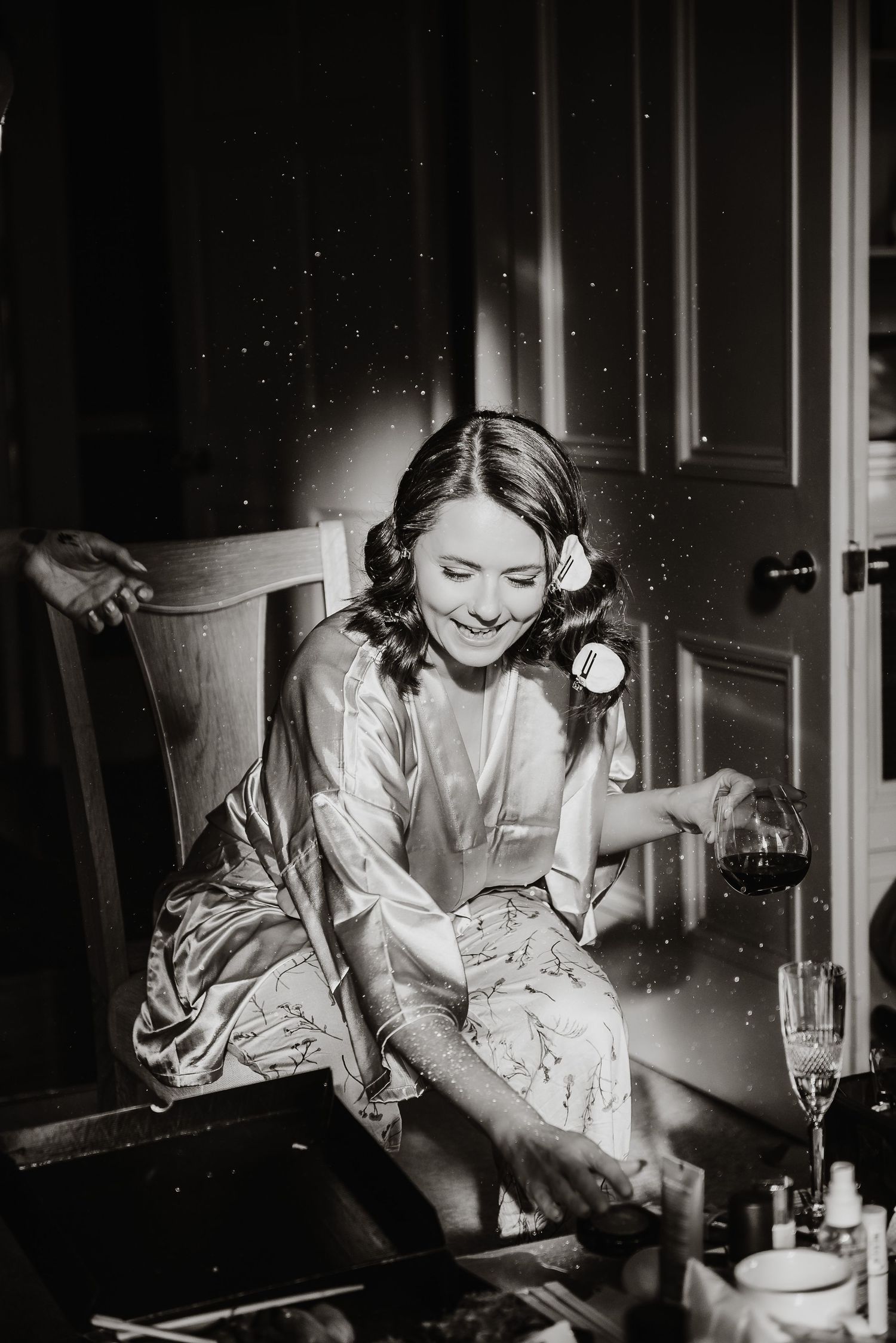Black and white vintage-style photograph of wedding preparations in dim lighting.