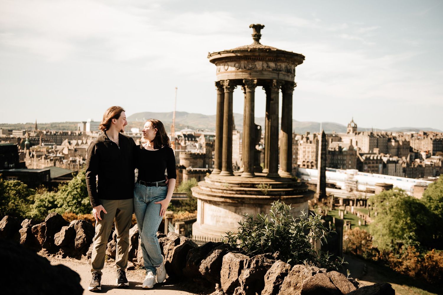 Couple admiring Edinburgh cityscape from Calton Hill near the Dugald Stewart Monument.
