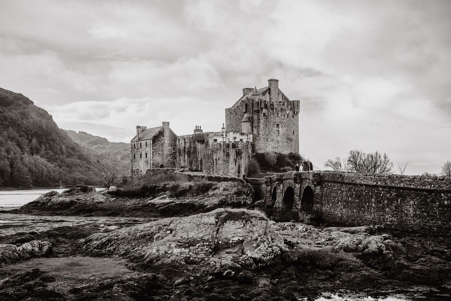 Moody black and white landscape of historic Scottish castle by the water.